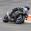 2025 Yamaha YZF-R1M on track. Rider leaning into a turn on the black and blue sportbike.
