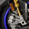 2025 Yamaha YZF-R1M front suspension detail. Öhlins forks, brakes, carbon fiber fairing, and blue wheel stripe.