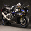2025 Yamaha YZF-R1M sportbike. Black and blue color scheme, carbon fiber accents, and gold front forks.