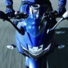 Riding a blue SUZUKI GIXXER SF 250 2024 motorcycle, the person sports a matching jacket as gleaming handlebars and mirrors highlight speed and style perfectly.