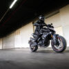 A person cruises through a dimly lit tunnel on a sleek black CFMOTO 800NK SPORT motorcycle.