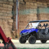 Blue 2024 Yamaha Viking III UTV parked near a barn with hay bales.