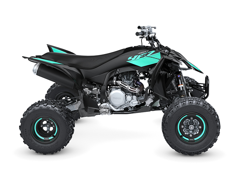 A black and teal YAMAHA YFZ450R 2024 ATV, featuring thick tires, is shown from a side view on a white background.