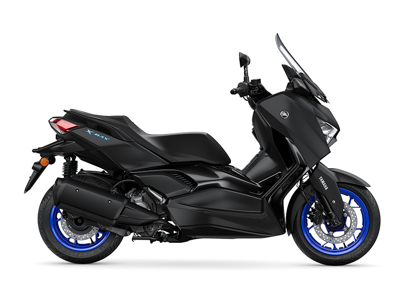 The YAMAHA XMAX 300 2024 (VOLUME 2) scooter, in black, showcases its sleek side profile with blue-rimmed wheels and an elegant windshield.