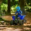 A person wearing a blue helmet and riding gear is driving a YAMAHA YZF50 2025 on a forest dirt trail.