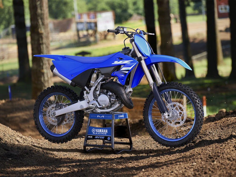 YAMAHA YZ125 2025 dirt bike on a stand amidst a wooded setting, placed on a dirt track.