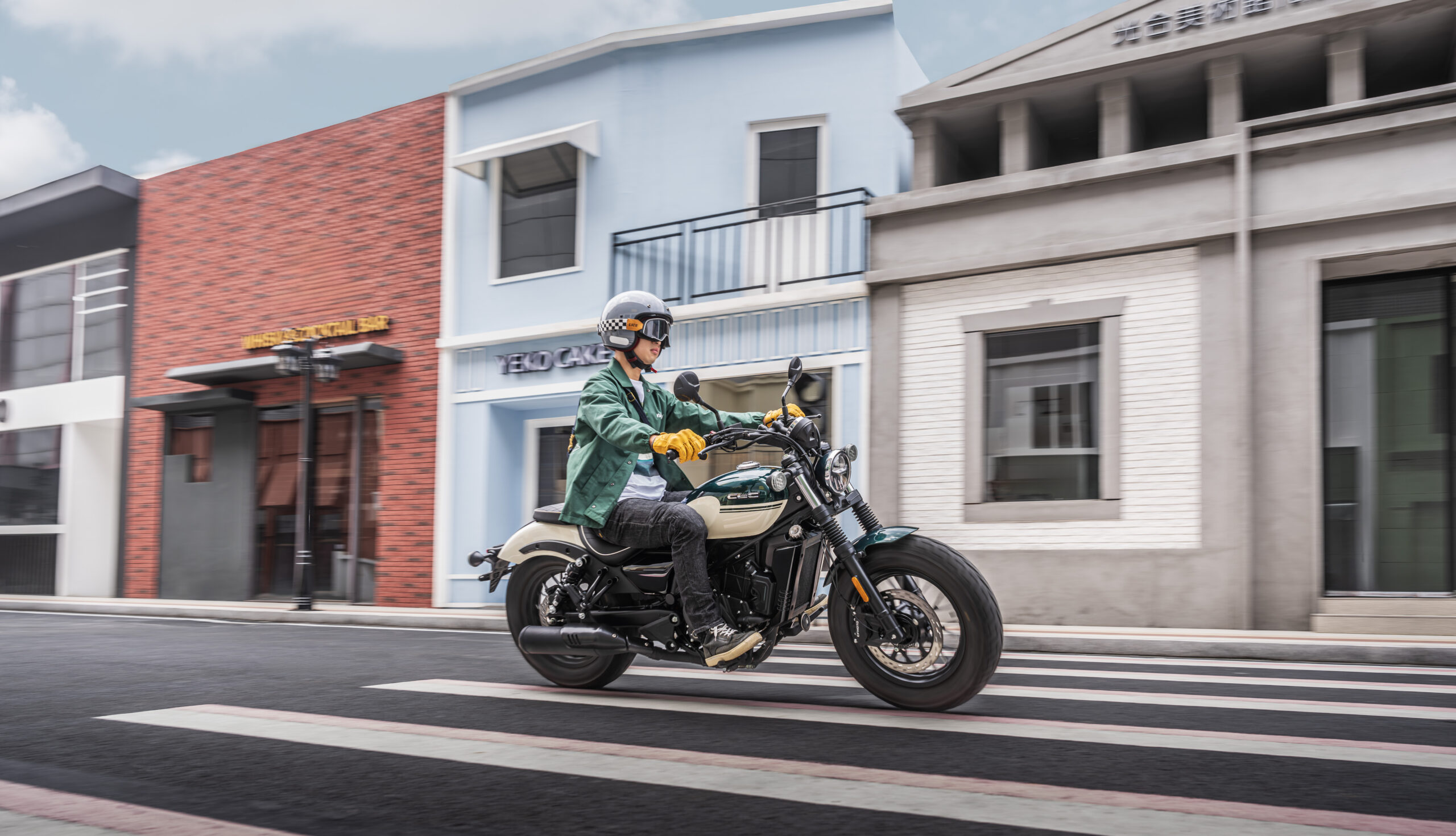 CFMOTO 250CL-C 6 Person riding a motorcycle on a city street, passing by colorful buildings.