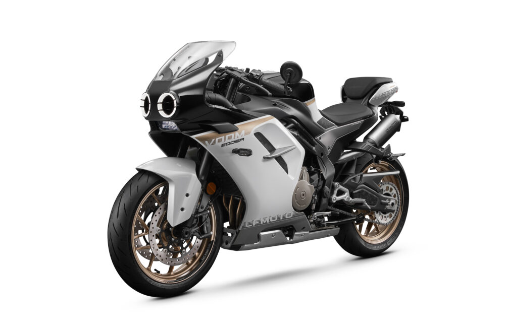 A silver and black CFMOTO 500SR VOOM sport motorcycle featuring gold wheels, dual round headlights, and aerodynamic bodywork, branded as "LE MOTO VROOM.