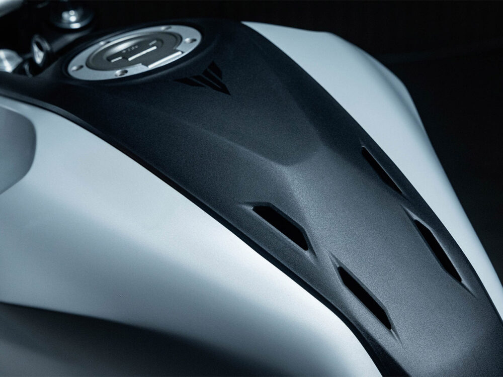Close-up of a YAMAHA MT-07 HO Y-AMT fuel tank with a matte black cover, triangular design, and vent-like slots.