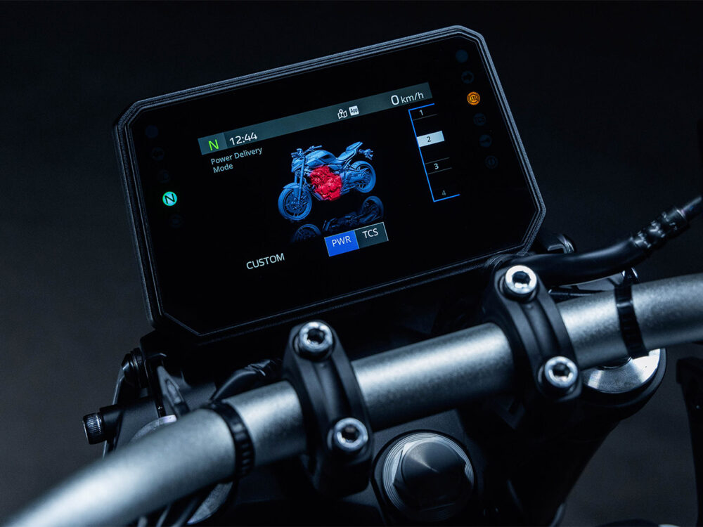Featuring a close-up of the YAMAHA MT-07 HO Y-AMT digital display, it shows an engine graphic, speedometer at 0 km/h, and ride mode options such as Power and Traction Control settings.
